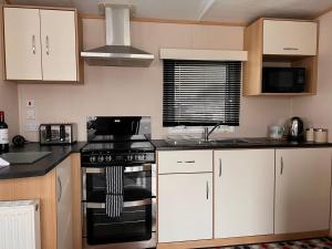 a kitchen with white cabinets and a stove top oven at Home by the sea, Hoburne Naish Resort, sleeps 4, on site leisure complex available in Milford on Sea