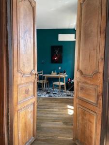 otwarte drzwi do jadalni ze stołem w obiekcie La Maison aux murs anciens et ses chambres w mieście Tarbes