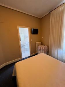 1 dormitorio con 1 cama, ventana y TV en Hotel Ramona, en Laredo