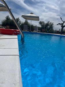 a swimming pool with an umbrella and blue water at Villa Evàlia - Private Villa With Pool -Malakonda ,Eretria ,Greece in Eretria