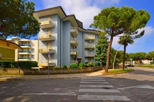 a large apartment building with a tree in front of it at Apartment in Lignano 21638 in Lignano Sabbiadoro