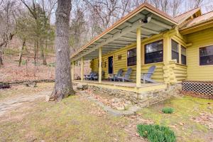 une maison jaune avec des chaises assises sur la terrasse couverte dans l'établissement Secluded Beaver Lake Cabin with Private Dock!, à Garfield