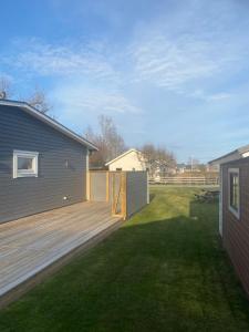 un patio trasero con terraza de madera junto a una casa en Monsunen, en Sölvesborg