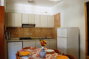 a kitchen with a table and a white refrigerator at Residence Milena in Milano Marittima