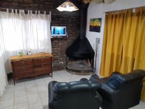 een woonkamer met een open haard, een bank en een televisie bij Lo de Quebu Cabaña en la Montaña in Potrerillos