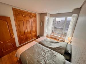 een slaapkamer met een bed en een groot raam bij Apartamento nuevo en el centro de Ourense 1 in Ourense