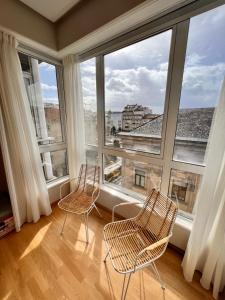 2 stoelen in een kamer met grote ramen bij Apartamento nuevo en el centro de Ourense 1 in Ourense