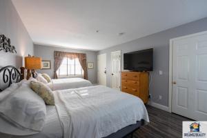 a bedroom with two beds and a flat screen tv at 2BR Walk-In Condo - Near the 76 Strip - Pool - FREE TICKETS INCLUDED - CLA-8 in Branson +24 photos