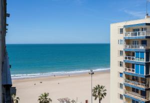 カディスにあるPlaya Victoria Paseo Marítimo 3 Roomsのビーチと建物の景色を望む
