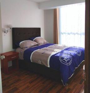 - une chambre avec un lit doté d'une couverture bleue et d'une fenêtre dans l'établissement Apartamento Cuzco, à Cusco