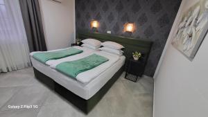 um quarto com uma cama com lençóis e almofadas verdes em Plitvice Inn em Jezerce