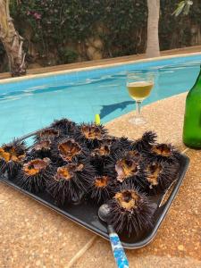 a tray of chestnuts on a table with a glass of wine at VILLA SOMONE avec PISCINE PRIVÉE in Somone
