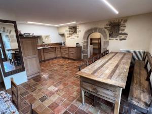 eine große Küche mit einem großen Holztisch und Stühlen in der Unterkunft Les Distinguées -Aux Bories de Prévinquières in Recoules-Prévinquières