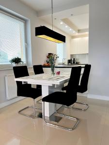 a kitchen with a white table and black chairs at Spanko w centrum in Zielona Góra