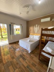 um quarto com uma cama branca e piso em madeira em Quintal da Praia em Prado
