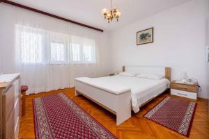a bedroom with a white bed and a red rug at Apartment in Crikvenica 5224 in Dramalj