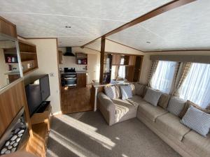 a living room with a couch and a tv at 6 Berth Caravan With Decking At Manor Park In Hunstanton Ref 23017h in Hunstanton