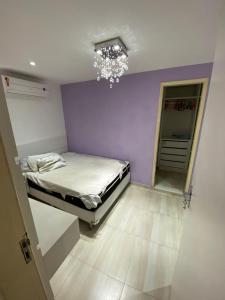 a small bedroom with a bed and a chandelier at Casa triplex com cobertura a 5 minutos da praia in Arraial do Cabo