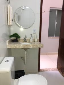 y baño con lavabo, espejo y aseo. en Flat Hotel, en Guanambi