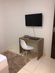 a desk with a monitor and a chair in a room at Flat Hotel in Guanamby