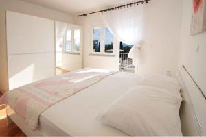 a white bedroom with a bed and a window at Two-Bedroom Apartment in Crikvenica X in Crikvenica