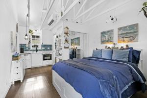 a white bedroom with a blue bed and a kitchen at 1 Mi to Lewisville Lake Fun Cozy Couples Retreat in Lake Dallas