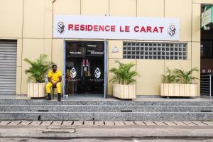 Ein Mann, der vor einem Wohnwagen sitzt in der Unterkunft Residence Le Carat in Douala