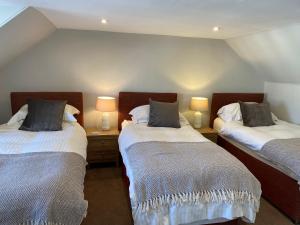 duas camas num quarto com duas lâmpadas nas mesas em Honeypot Guest House em Crail