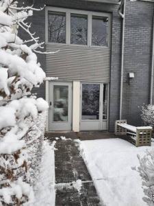 ein schneebedecktes Haus mit einer Tür und einer Bank in der Unterkunft 4-Bedroom-Apt for 7/Oslo Central in Oslo