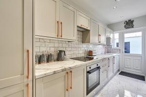 a kitchen with white cabinets and a stove top oven at Belfast Luxury Lets - Windsor Townhouse in Belfast