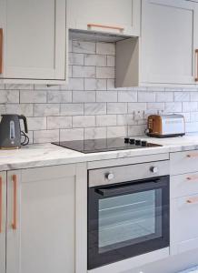 a kitchen with white cabinets and a stove top oven at Belfast Luxury Lets - Windsor Townhouse in Belfast