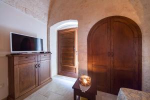 a living room with a tv and a wooden cabinet at La corte di Ercole in Alberobello