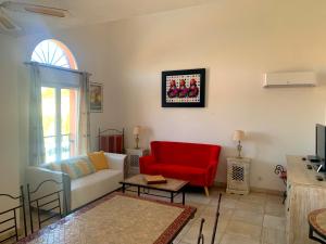 sala de estar con sofá y silla roja en Terrasse du golf en Béziers