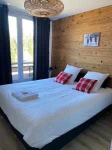 Résidence les 3 Sommets في Sarcenas: غرفة نوم مع سرير أبيض كبير مع وسادتين حمراء