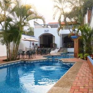 a pool with tables and chairs and a house at Los Ángeles Hotel in Jalpan de Serra