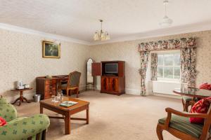 a living room with a television and a table at Cally Palace Hotel & Golf Course in Gatehouse of Fleet