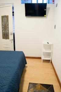 a bedroom with a bed and a tv on a wall at Hostal Lucas Corferias - Habitaciones Privadas in Bogotá