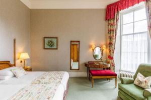 um quarto de hotel com uma cama e uma cadeira e uma janela em Cally Palace Hotel & Golf Course em Gatehouse of Fleet
