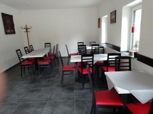 une salle à manger avec des tables blanches et des chaises rouges dans l'établissement Penzion Litohlavy 17 - Na samotě u lesa, à Králŭv Dvŭr