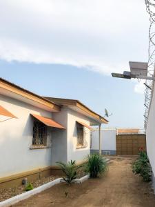 a white house with two windows and a fence at Chez Catherine et Gabriel in Bangui