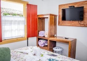 Habitación pequeña con cama y TV. en Flats Casa de Violeta, en Tiradentes
