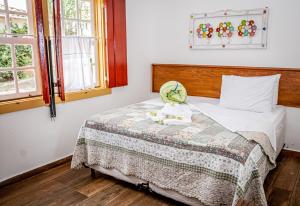 a bedroom with a bed with a blanket and windows at Flats Casa de Violeta in Tiradentes