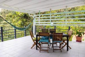 un patio con mesa y sillas en un porche en Bold'Air piscine, vue mer en Le Vauclin