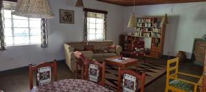 a living room with a couch and a table and chairs at Mutolere Coffee Pot Guest Houses in Kisoro