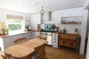 a kitchen with white cabinets and a wooden table with a wooden table at Welcoming 2 bed townhouse near town centre & beach in Kent