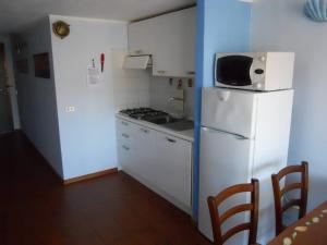 a small kitchen with a white refrigerator and a microwave at Appartamento con piscina e aria condizionata in La Maddalena