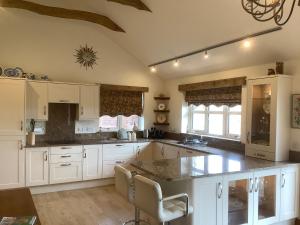 a kitchen with white cabinets and a large island at Orchard Cottage, Clematis cottages, Stamford. Accessible luxury home. in Stamford