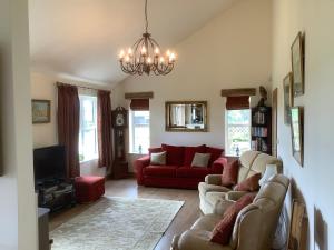 a living room with a red couch and a chandelier at Orchard Cottage, Clematis cottages, Stamford. Accessible luxury home. in Stamford