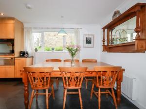 cocina con mesa de madera y sillas en Bro Tref Cottage, en Newquay