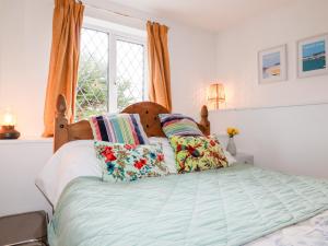 a bedroom with a bed with pillows and a window at Bro Tref Cottage in Newquay